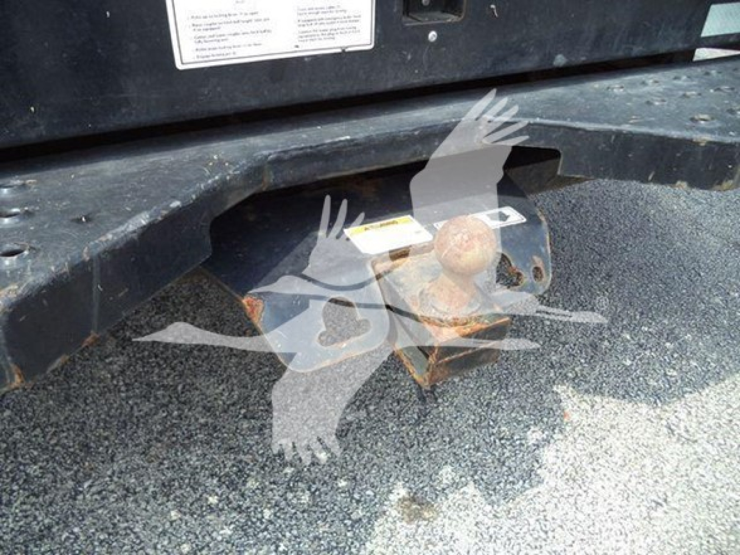 GMC G3500 hitch area with rusted hitch receiver and hitch ball; sticker labels on the chassis; part of rear bumper and frame visible.