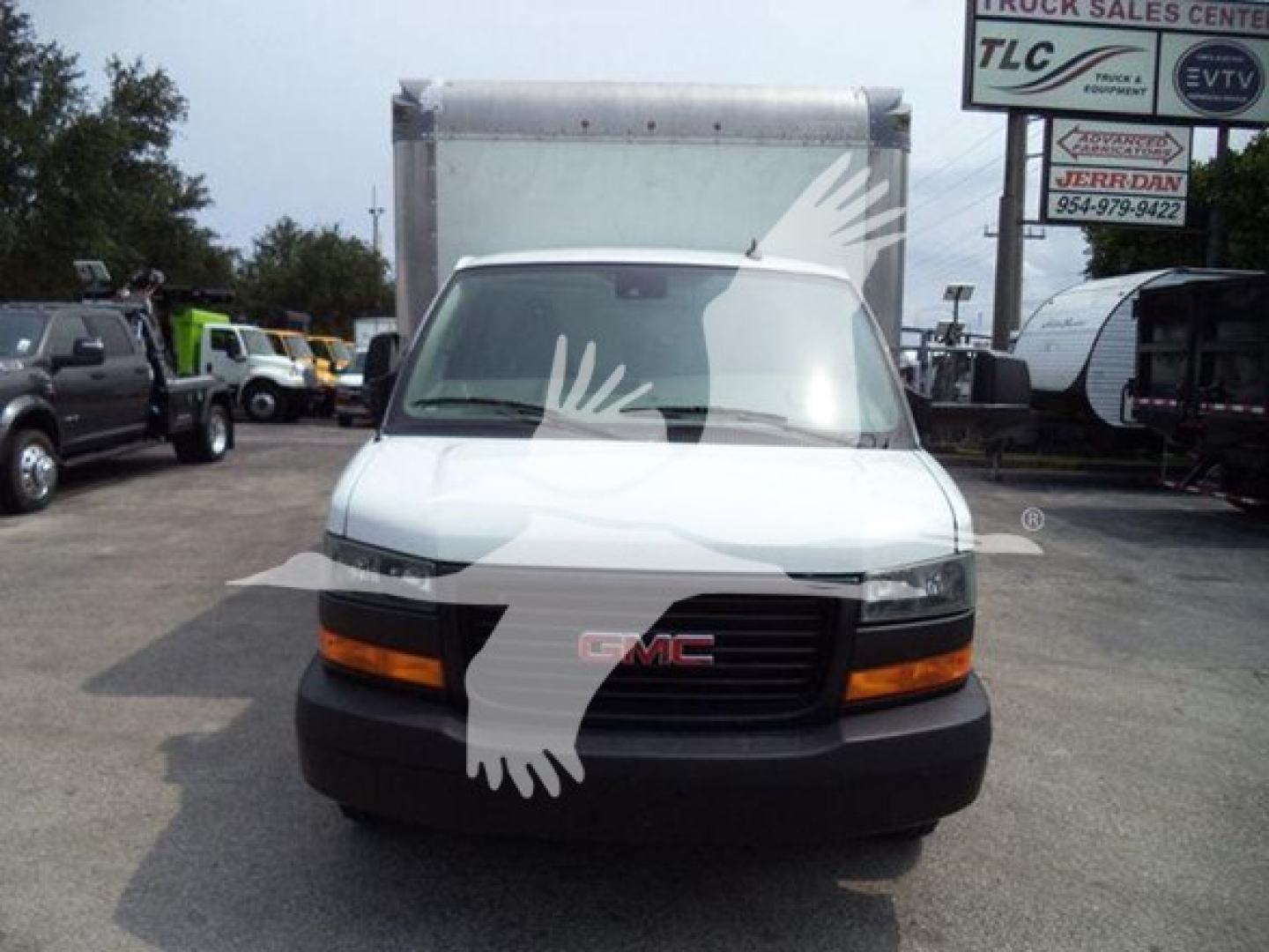GMC G3500 front view showing grille with GMC badge and headlights in a cargo van, parking lot background.