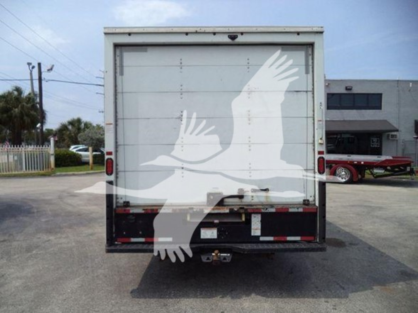 Rear view of a GMC G3500 box truck with a stylized white eagle decal on the back doors.