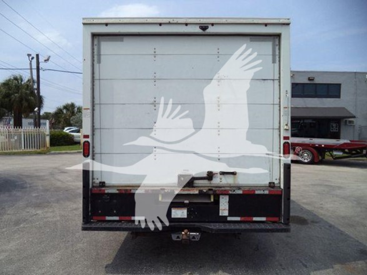 Rear view of a GMC G3500 box truck with a white cargo door; no legible text visible on the door.