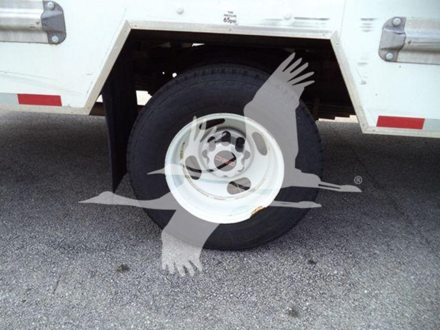 GMC G3500 wheel and tire view, side of commercial truck body with white steel rim and tire, part of cargo box visible.