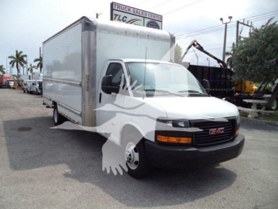 GMC G3500 box truck in a dealership lot; side of cargo box and cab visible; company logo watermark overlay; background shows other trucks and a sign reading 'TRUCK SALES CENTER'.