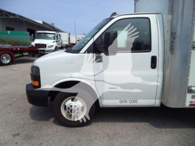 GMC G3500 low front-side view showing cab and part of cargo box, with GVW 12300 label on door.