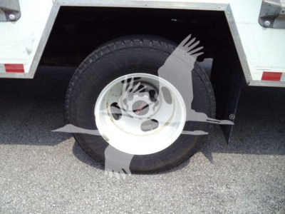 GMC G3500 wheel and tire mounted on white utility body side view showing wheel hub and tire treads.