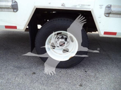 GMC G3500 wheel and tire view, side of commercial truck body with white steel rim and tire, part of cargo box visible.