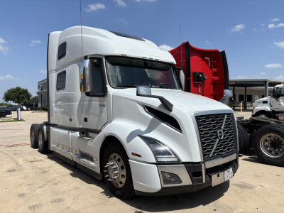 Volvo VNL64T860 truck in a yard showing front grille, headlights, and sleeper cab with white paint and black trim.