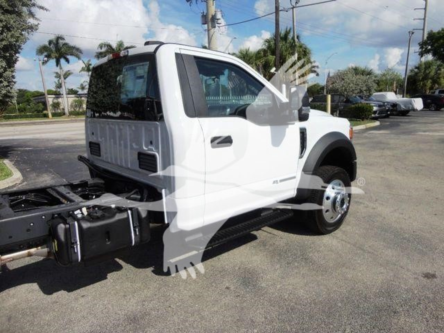 Ford F-550 cab and chassis with chassis exposed at front, white exterior, side view showing front fender and door, dump truck configuration not yet mounted
