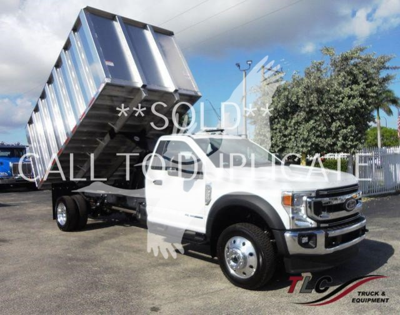Ford F-550 dump truck with raised dump bed in white cab and chrome wheels