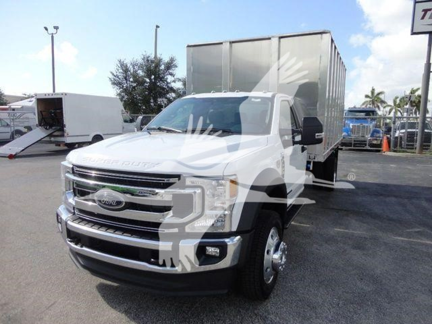 Ford F-550 dump truck with white cab and aluminum dump body, front grille, dual mirrors, daytime running lights, in a dealership lot.
