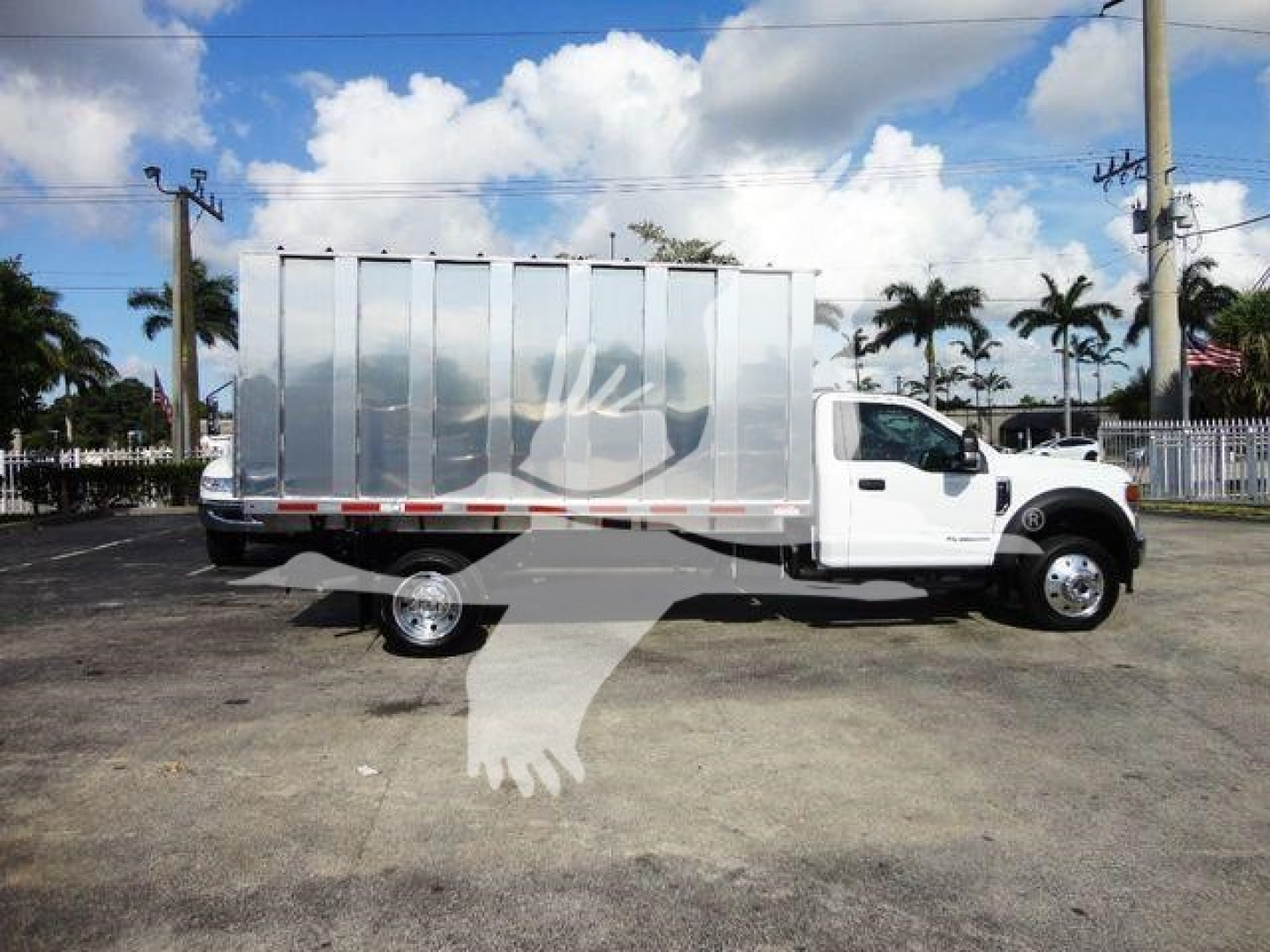 Truck bed view of a white 2022 Ford F550 dump truck with a silver metal cargo body and dual rear wheels, side profile visible.