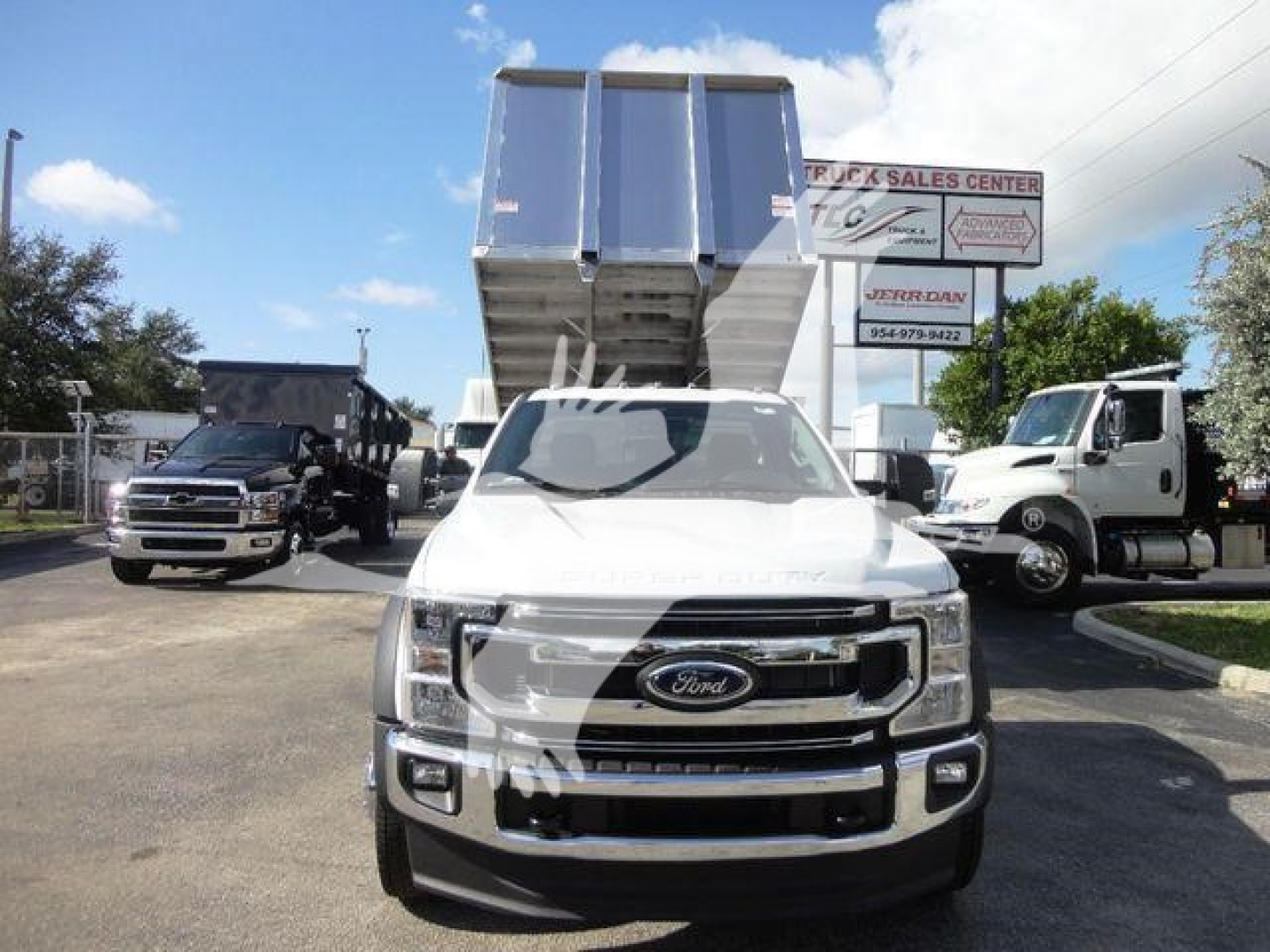 Ford F-550 dump truck with dump body raised, front view in dealership lot.