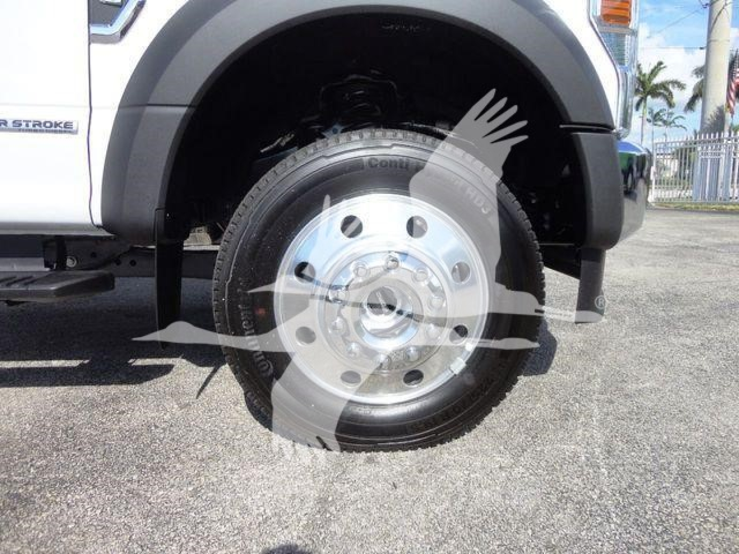 Truck wheel and front fender of a 2022 Ford F-550 dump truck showing aluminum wheel and tire, with partial side badge and truck body details