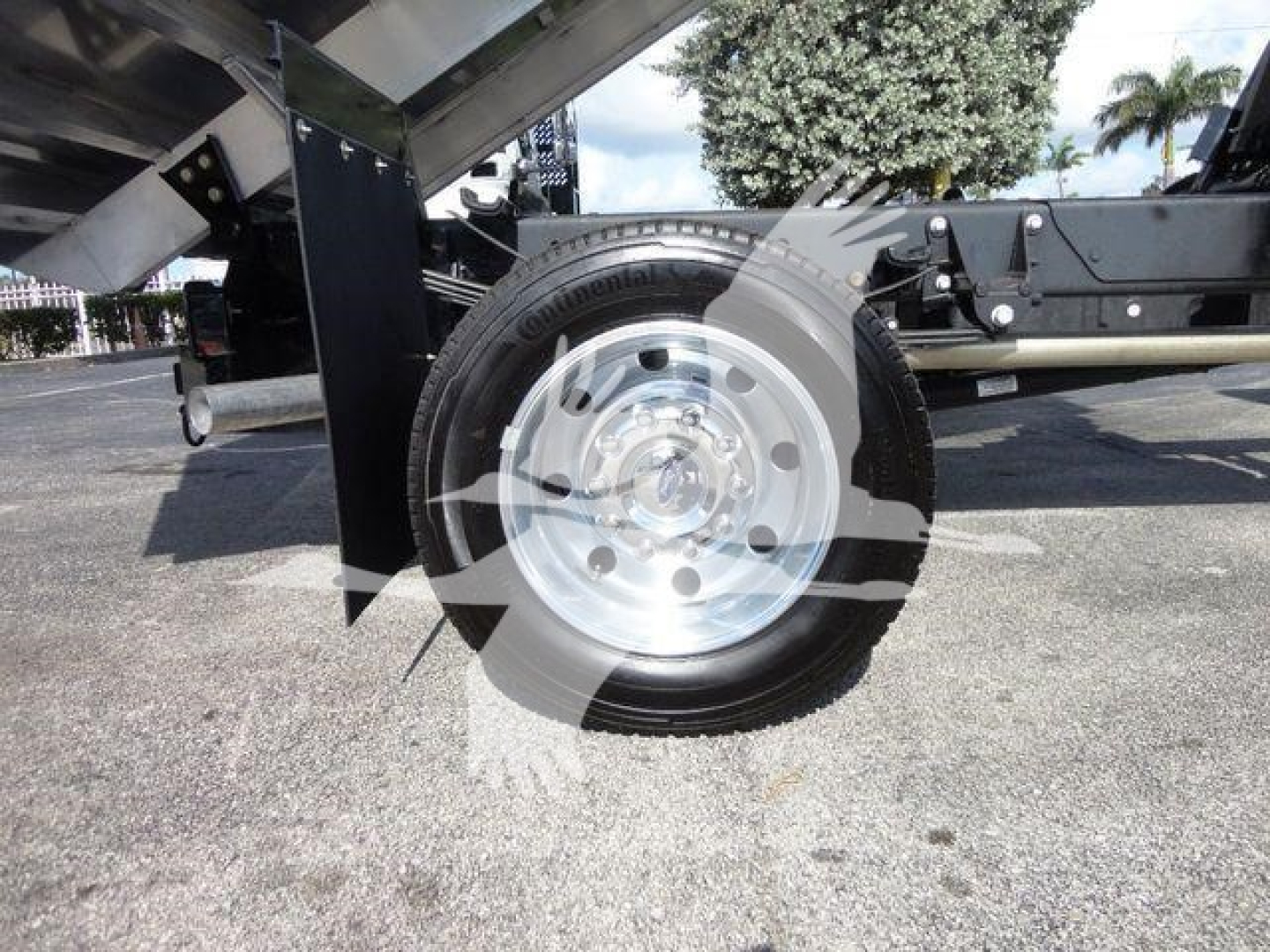 Ford F550 dump truck wheel and semi-trailer hitch area showing polished steel rim and tire.
