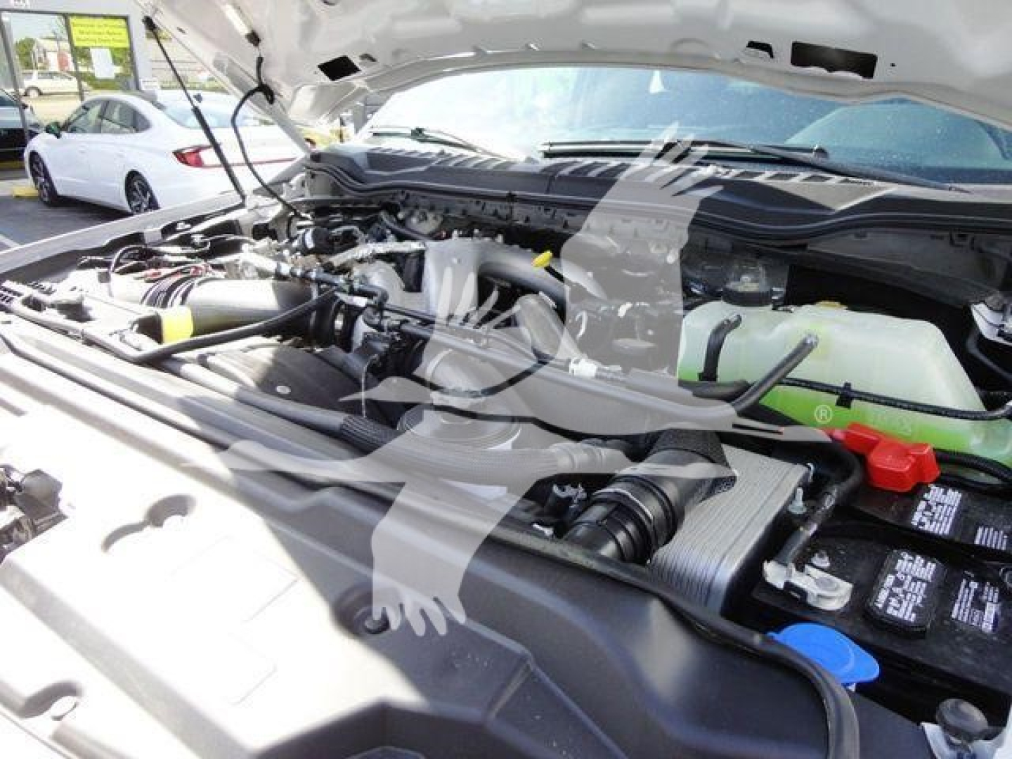 Ford F550 engine bay view showing battery, coolant reservoir, and various hoses and components.