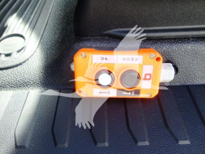 Orange dual switch device with labels mounted on a black surface in a Ford F550 dump truck bed area