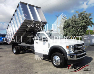 Ford F-550 dump truck with raised dump bed in white cab and chrome wheels
