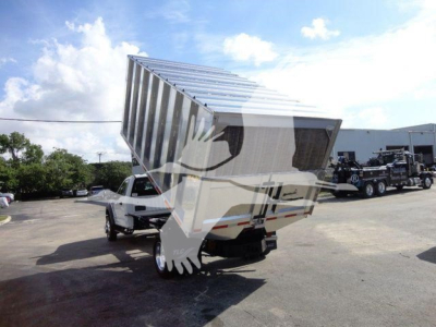 Ford F-550 dump truck with raised tipped bed in front view showing dump mechanism and truck cab.