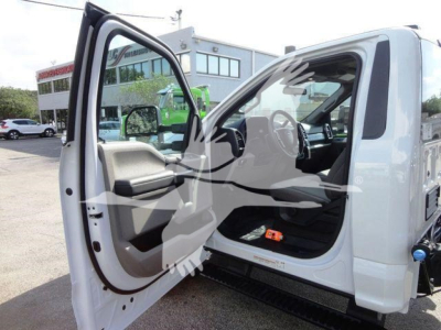 Ford F-550 dump truck cab interior with driver door open showing steering wheel, dashboard, and passenger seat.