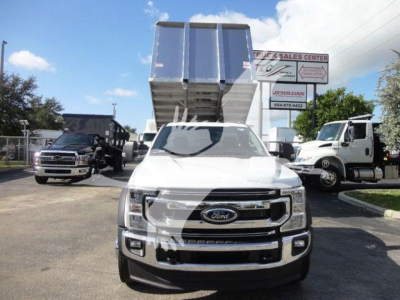 Ford F-550 dump truck with dump body raised, front view in dealership lot.