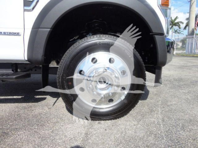 Truck wheel and front fender of a 2022 Ford F-550 dump truck showing aluminum wheel and tire, with partial side badge and truck body details