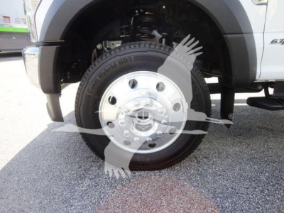 Ford F-550 dump truck front wheel and tire view showing chrome hub, wheel well, and suspension components.
