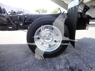 Ford F-550 front wheel well and chassis showing spare tire, steel wheel, and dump body support framework.