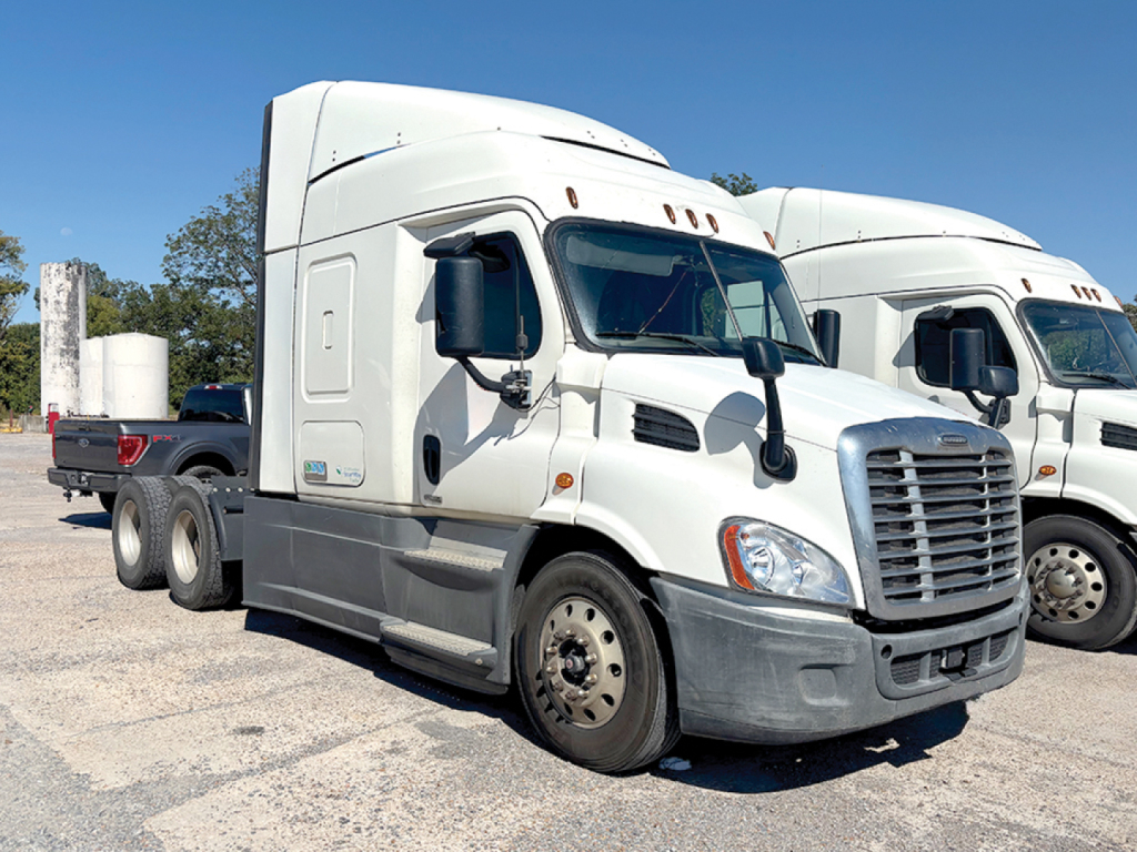 Freightliner Cascadia113 tractor cab in a parking lot with another truck in background.