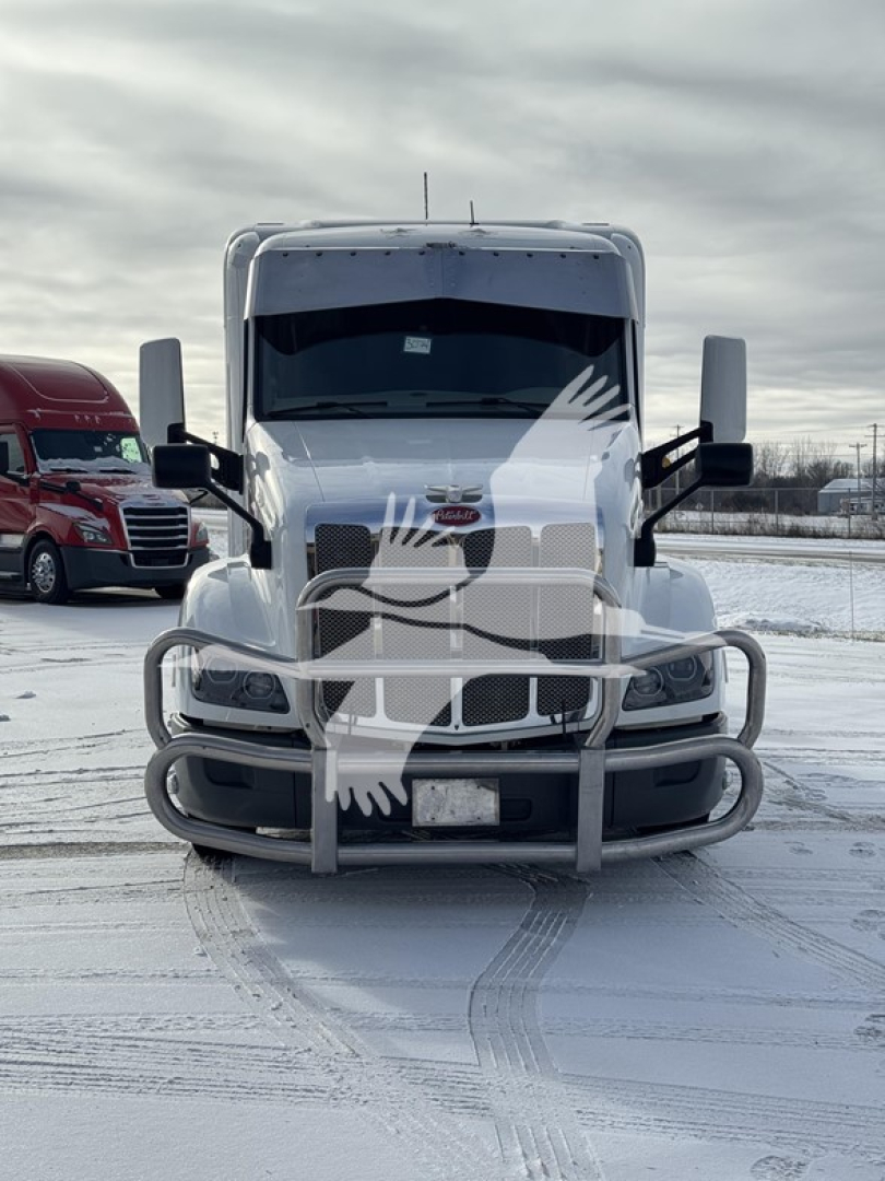 Peterbilt 579 conventional sleeper truck front view with bumper guard and snow on ground.