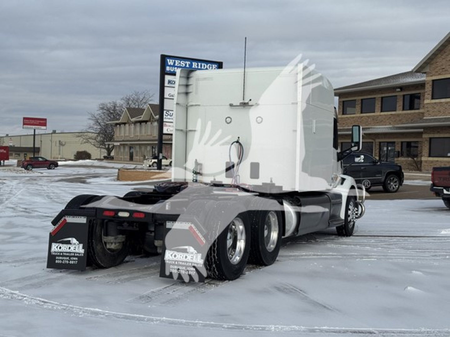 Peterbilt 579 tractor in a parking lot, view of rear and sleeper cab; includes snow on ground and dealership backdrop.