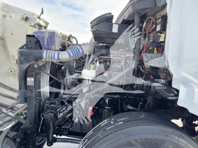 Peterbilt 579 engine bay and front chassis showing radiator, hoses, wiring, and steering area with exposed engine components.