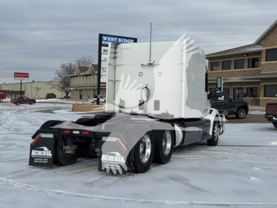 Peterbilt 579 tractor in a parking lot, view of rear and sleeper cab; includes snow on ground and dealership backdrop.
