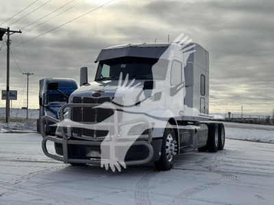 Peterbilt 579 truck in a snowy lot, white cab with sleeper, front grille, and dual rear axles visible.