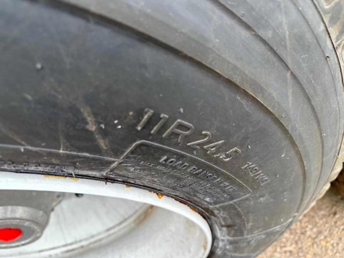 Tire showing sidewall markings 11R24.5, Load Range H, Long Haul on trailer wheel.