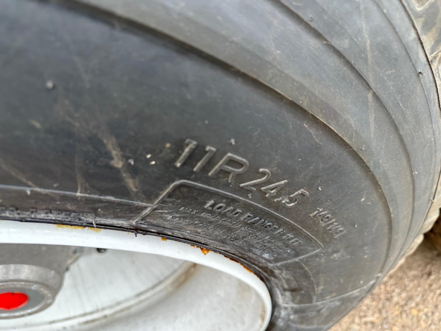 Tire sidewall with embossed markings: LR24.5 16.1R? and faint branding; close-up of wheel and rim on a dump trailer.