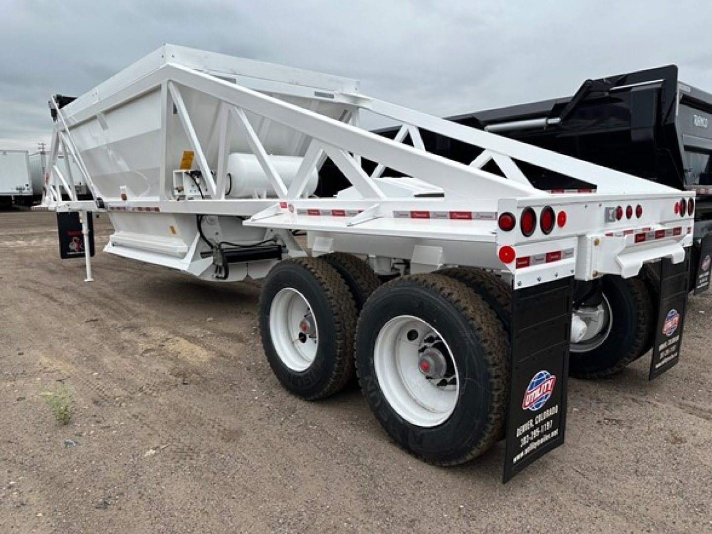 Ranco LW21-40 dump trailer showing dual axles and white frame with diamond plate fenders and rear lighting