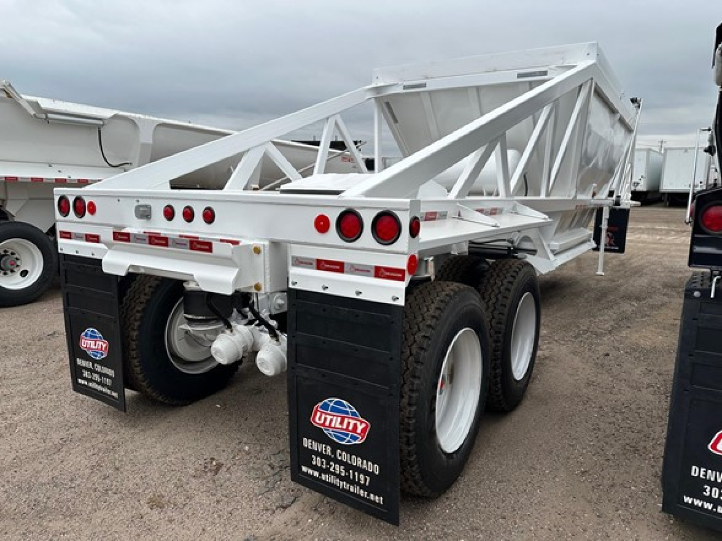 Quad-axle dump trailer showing LW21-40 model with white powder-coated frame and dual rear axles, heavy-duty tires, Utility/Denver dealer mudflaps.