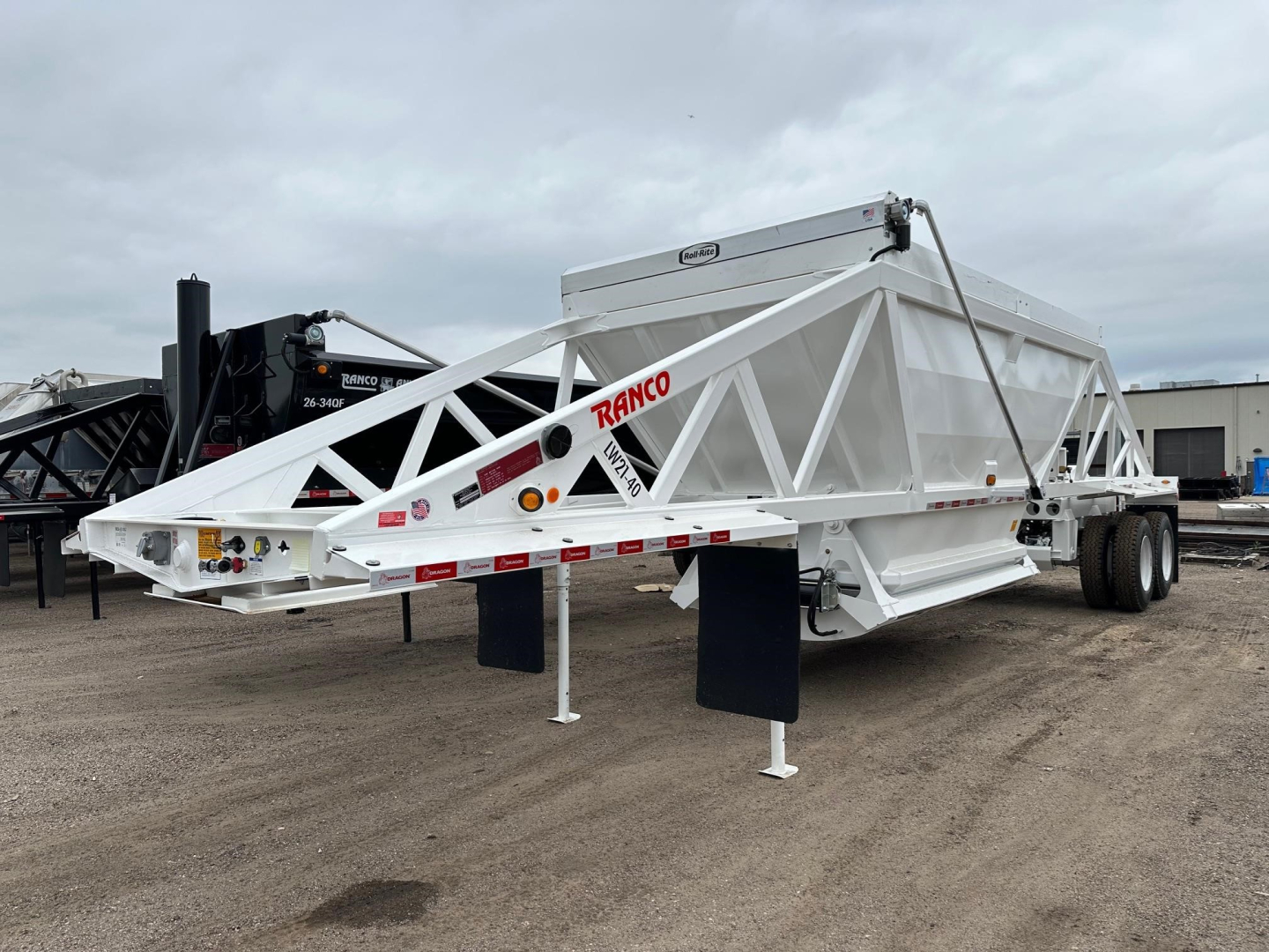 Ranco LW21-40 dump trailer on a dirt lot, white rectangular body with lattice frame, dual rear axles, landing gear, and red RANCO logo visible on side.