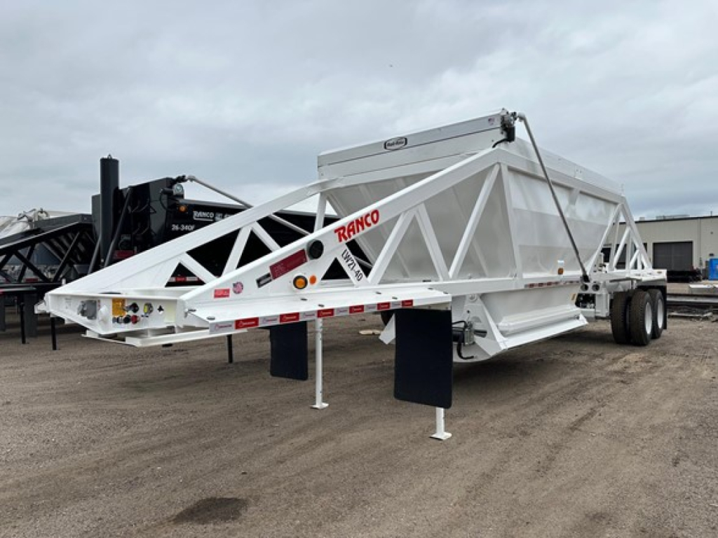 Ranco LW21-40 trailer in white with lattice frame, dual rear wheels, and landing legs visible; side text reads RANCO on the frame; dump trailer in a yard.