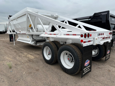 Ranco LW21-40 dump trailer in white with dual rear axles, showing side rails and rear lights. Brand labels on mudflaps and tires visible.