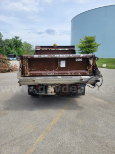 Rear view of a brown dump bed plow truck with 226 on tailgate, Henderson-style heavy-duty dump bed, in-service condition.