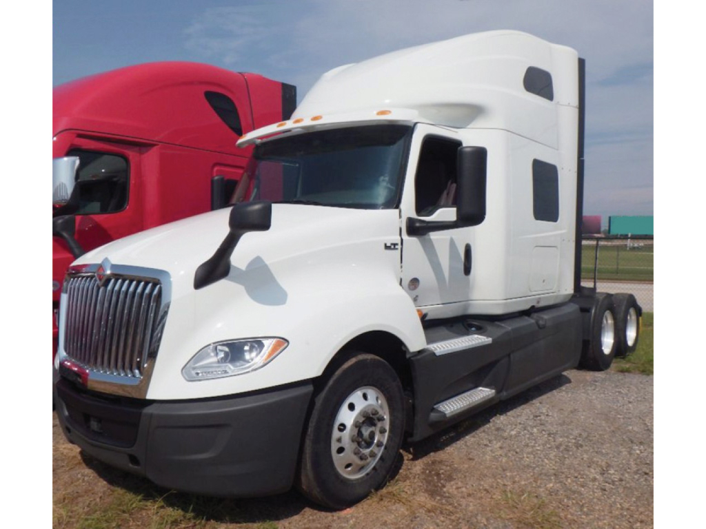 Truck cab in white and sleeper International LT625 showing front grille and side view with large mirrors.