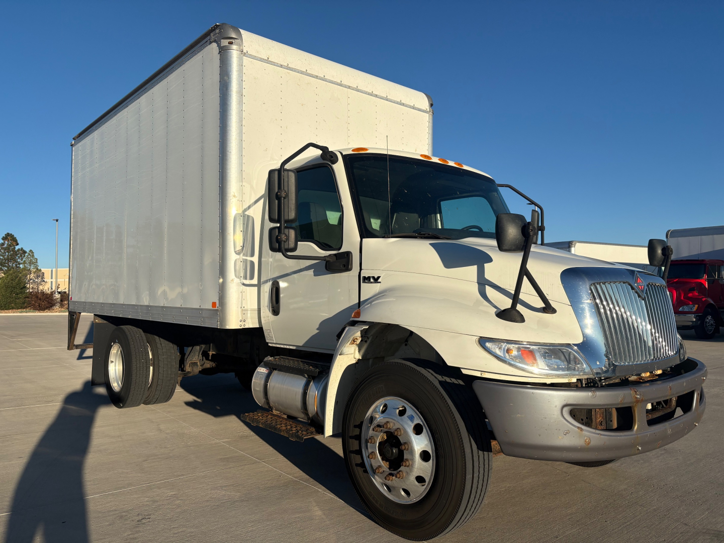 Truck cab and box truck side view showing International MV cab with box body, front grille, headlights, and dual rear wheels.