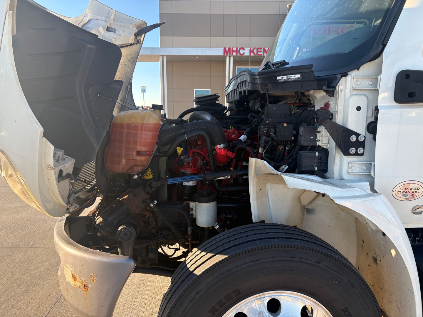 International MV607 engine bay showing coolant reservoir, red turbo/intercooler piping, and open hood with exposed engine components.