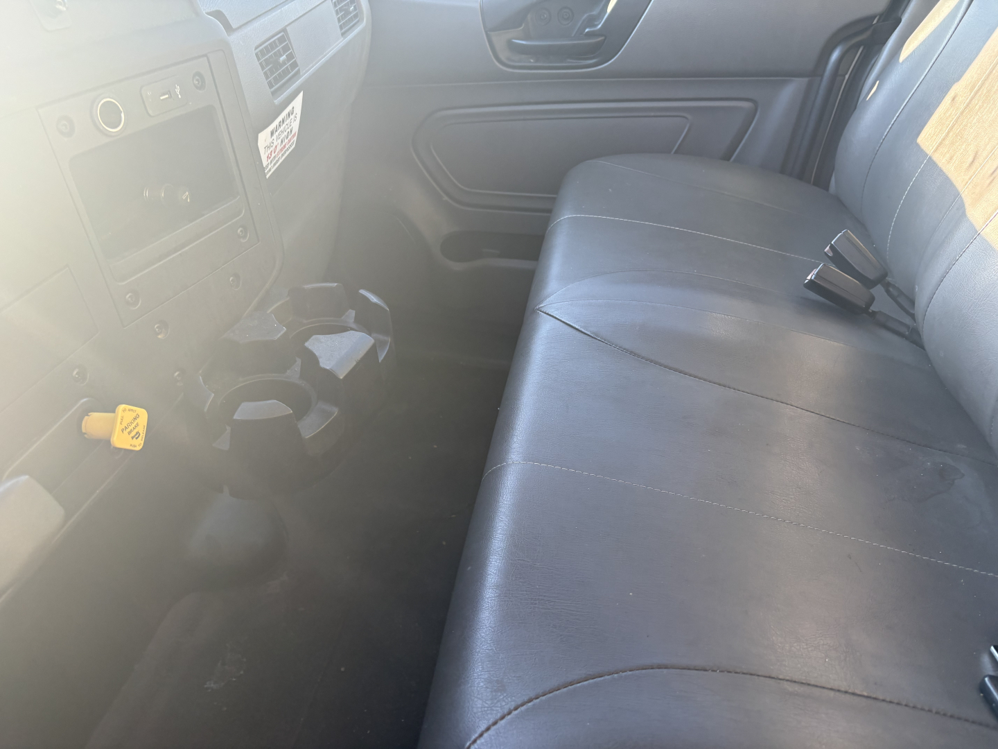 Truck interior showing front dash with controls and a long bench seat in a used 2021 International MV607. Visible text includes no obvious label text due to glare.