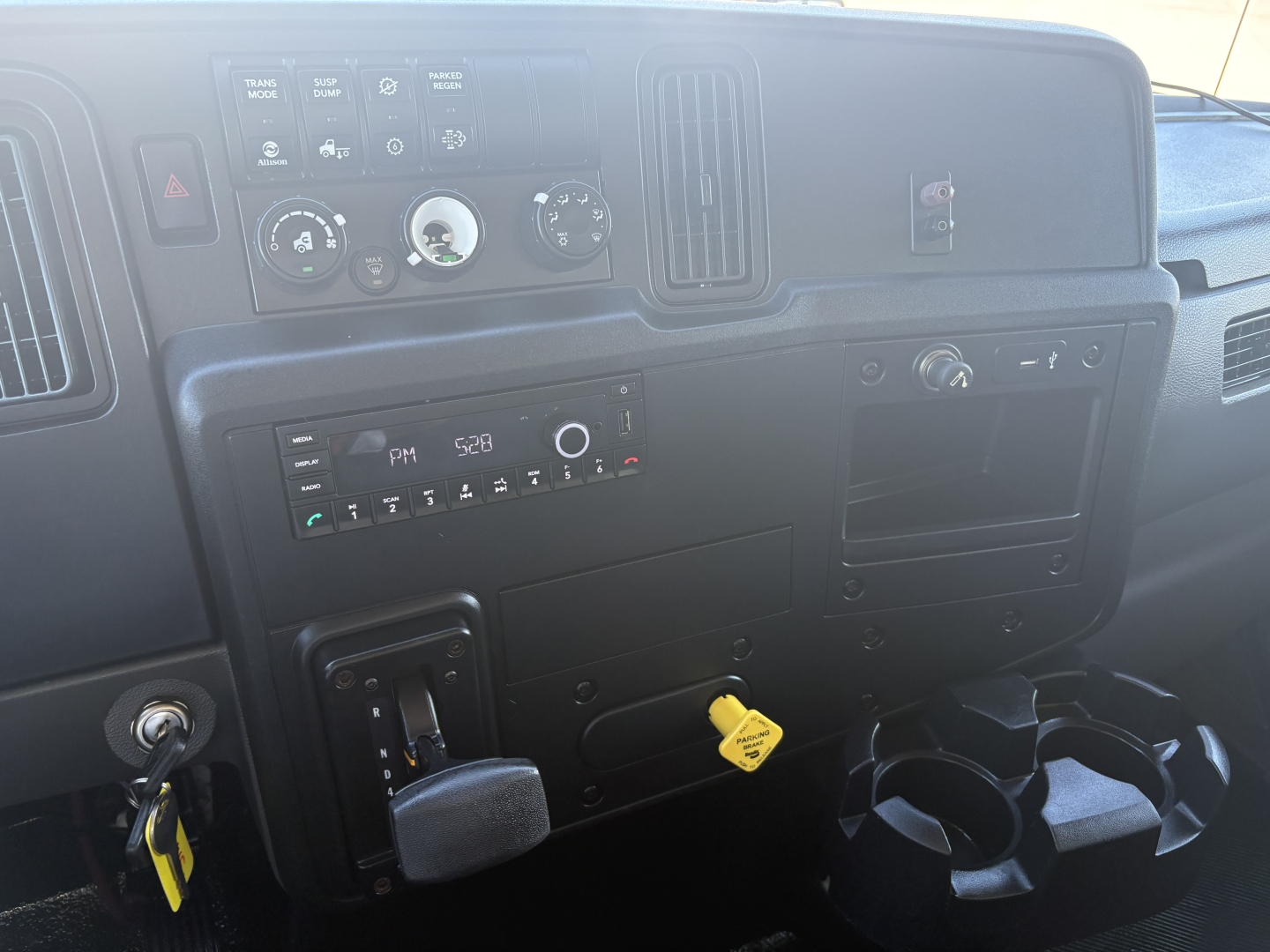 Interior of a 2021 International MV607 dash showing steering column, instrument panel, climate controls, ignition with key, and cup holders.