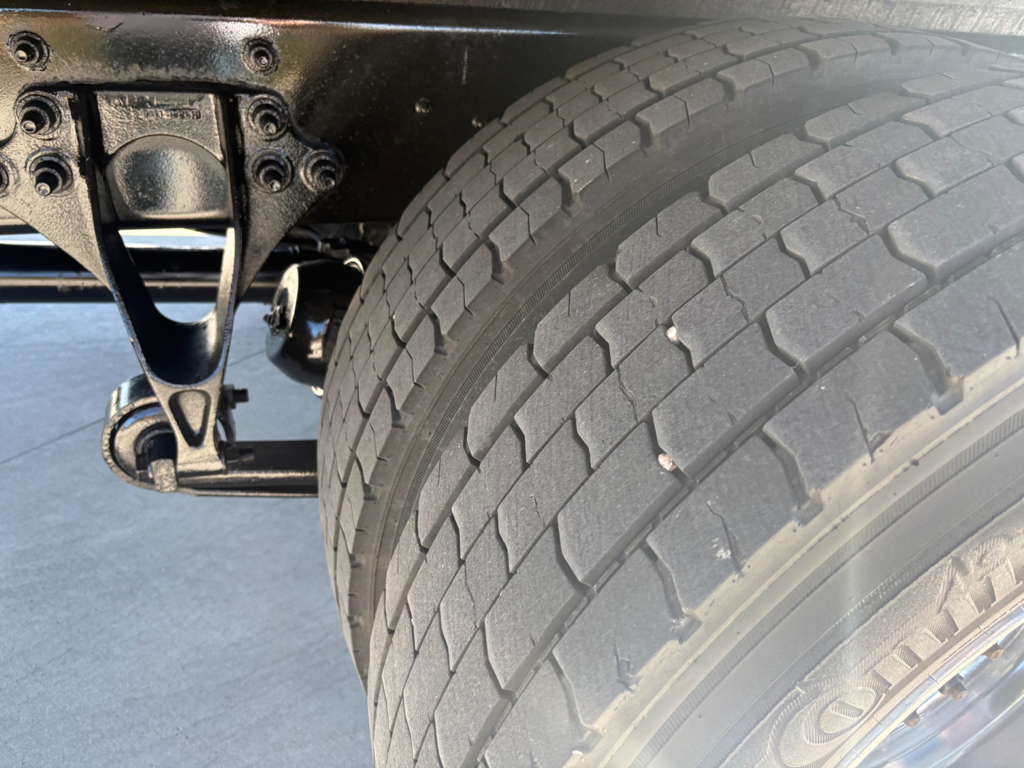 Truck rear suspension and dual rear tire shown with wheel and axle components visible under the chassis.