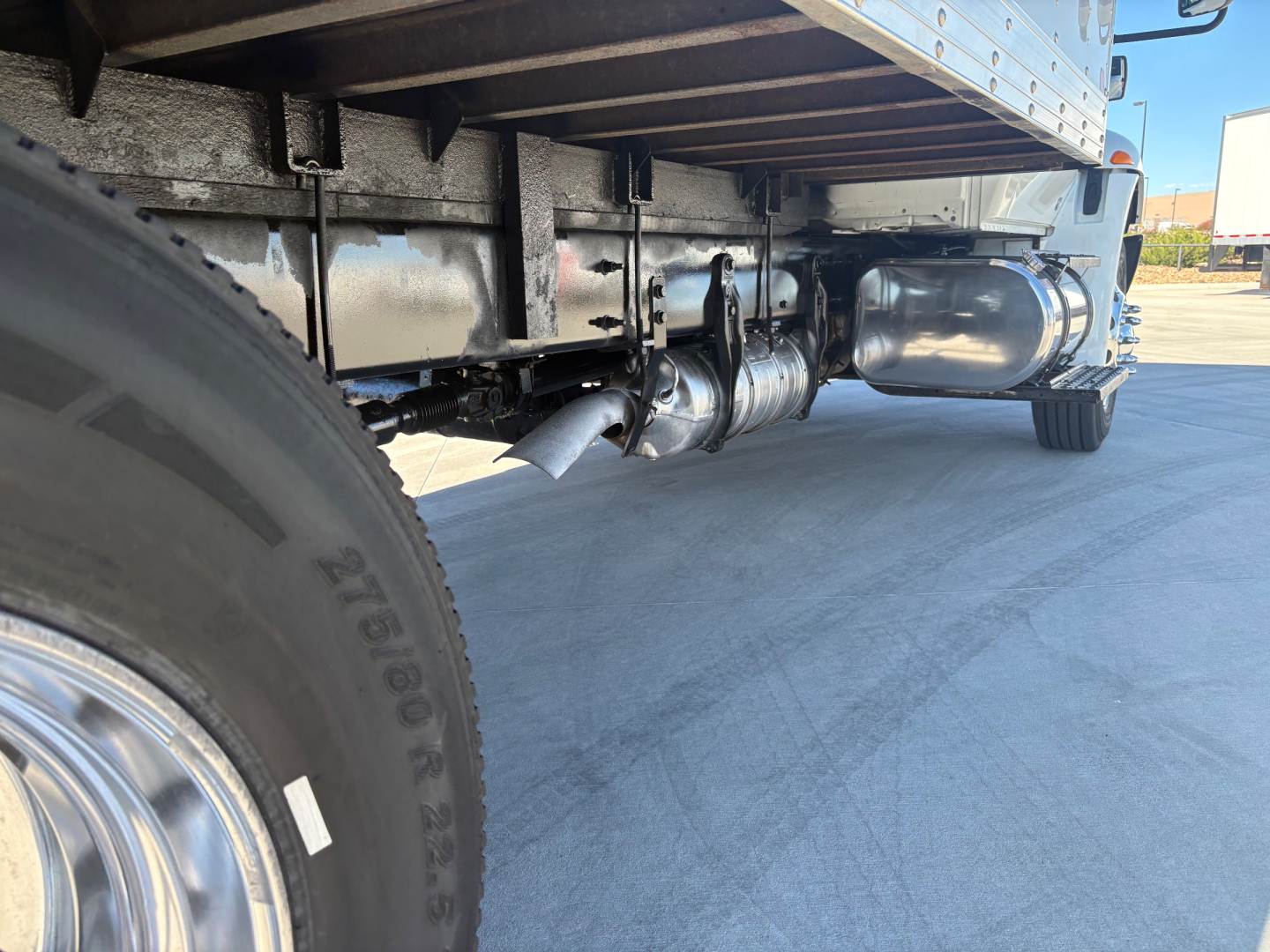 Truck undercarriage showing diesel exhaust pipe, rear axle, and fuel tank with chrome chrome exhaust and chassis components.