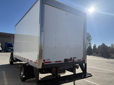 Box truck rear view showing large white roll-up door and bumper with reflective tape.