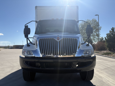Truck front view showing grille and headlights of a 2021 International MV607 box truck with chrome bumper and large side mirrors.