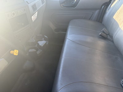 Truck interior showing front dash with controls and a long bench seat in a used 2021 International MV607. Visible text includes no obvious label text due to glare.